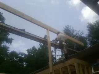 Carpenter setting a ridge beam over a new addition frame — Ice Dam Removal by Roofing Brothers in Amazonia