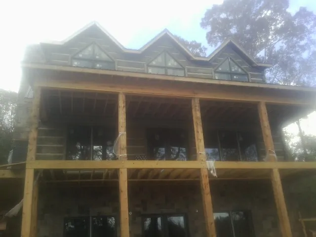 Dormers and porch framing on a large log home under construction — Roof Coating work by our crew in Amazonia