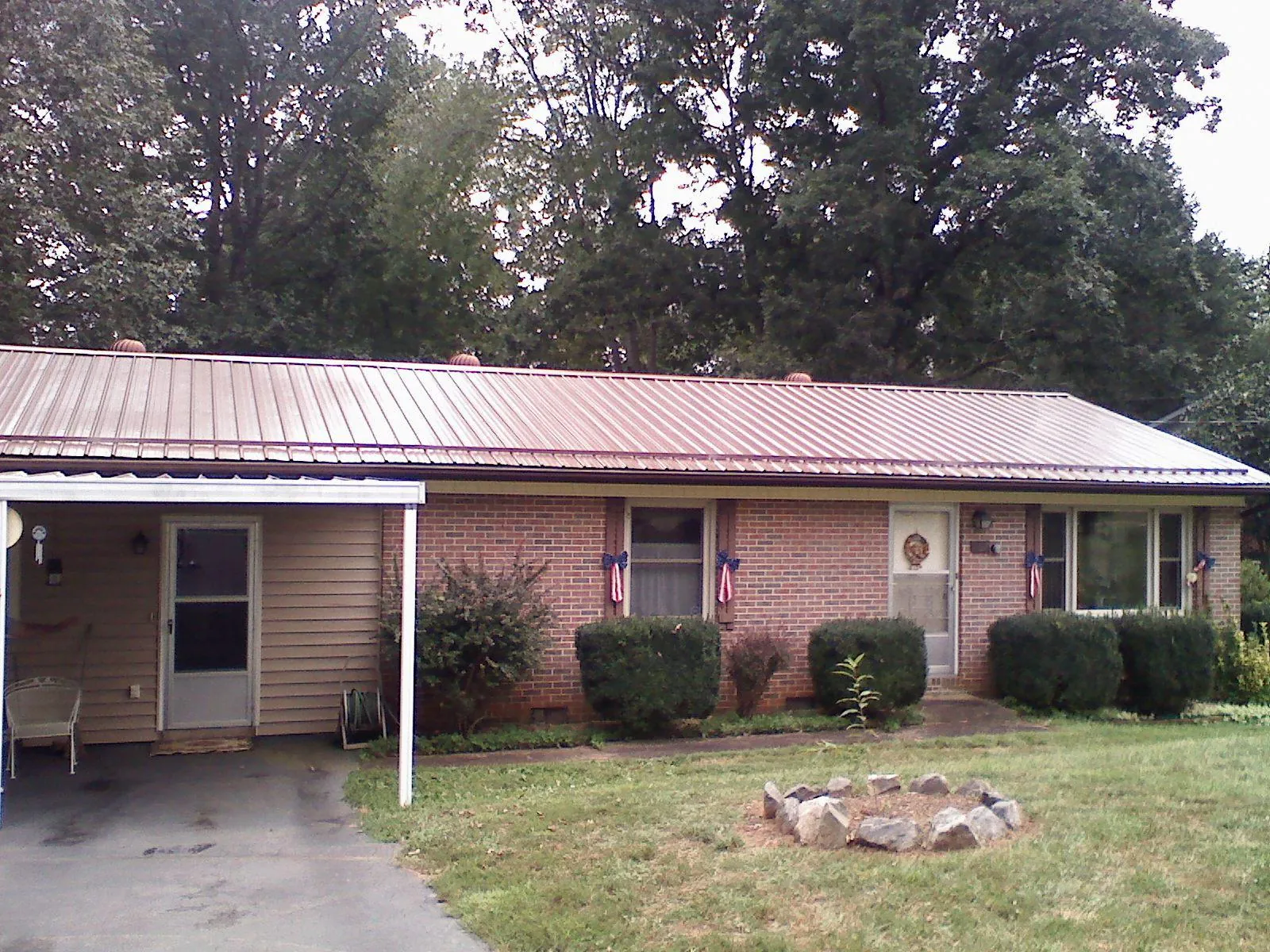 Bronze metal roof and carport on a brick ranch home — Roof Repair work by our crew in Amazonia
