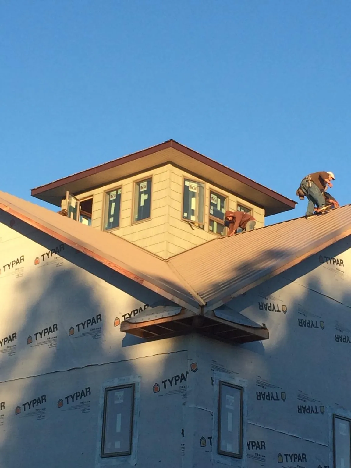Roofers working around a rooftop cupola on a new metal roof at sunset — Roof Waterproofing in Amazonia by Roofing Brothers